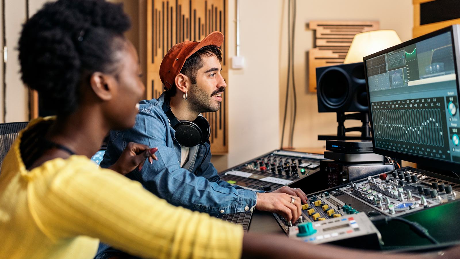 Two people learning audio production at a studio mixing desk