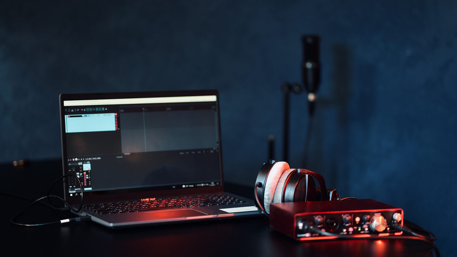 Home studio desk with a USB audio interface, laptop, headphones and microphone