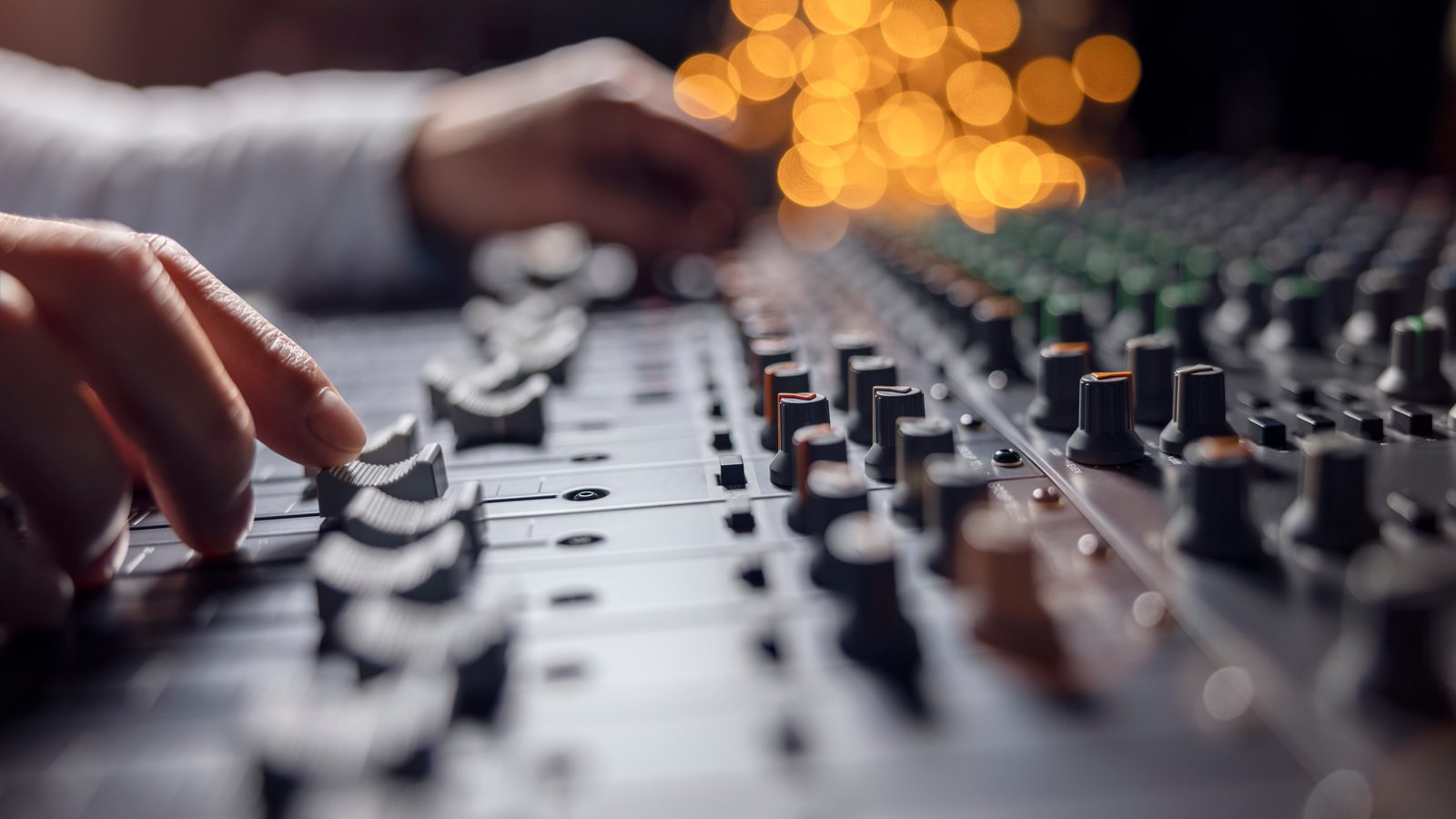 Hands adjusting the faders and EQ knobs on a mixing desk