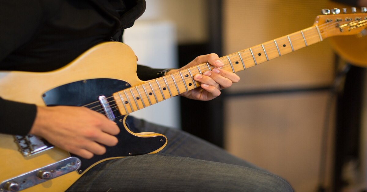 A person learning to play the electric guitar online while practicing on a Telecaster.